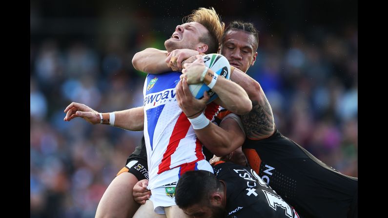 Nathan Ross of the Newcastle Knights is tackled by several of the Wests Tigers during a National Rugby League match in Sydney on Saturday, August 15.