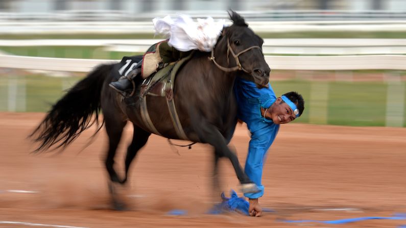 A Mongolian rider picks up "hadas," or scarves, while riding a horse Sunday, August 16, at the National Traditional Games of Ethnic Minorities of China.