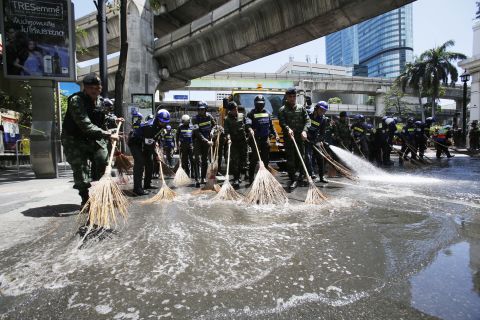 Police and soldiers wash the street in front of the Erawan Shrine.