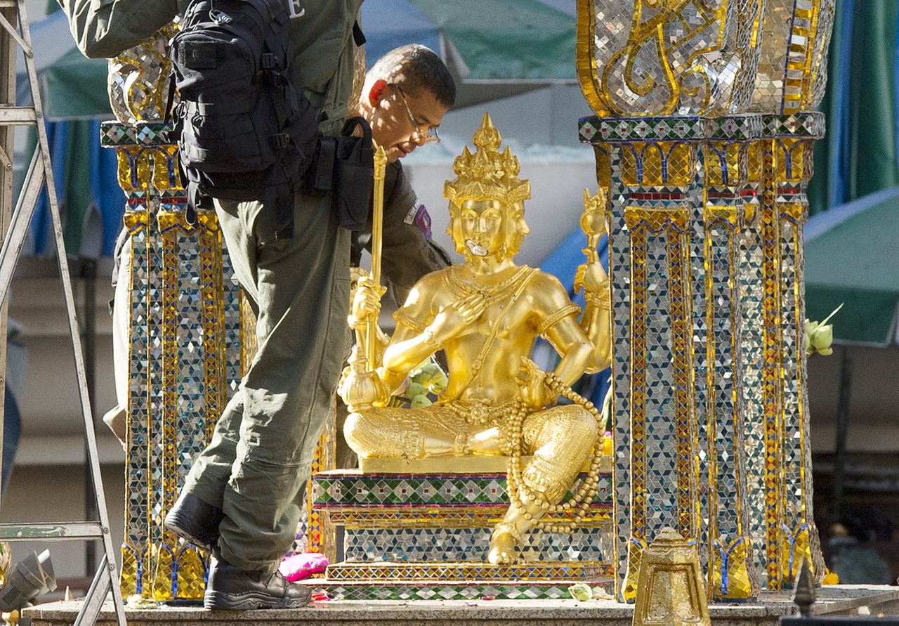 Police investigators work near the statue of Phra Phrom, the Thai interpretation of the Hindu god Brahma, at the Erawan Shrine the morning after the explosion. 