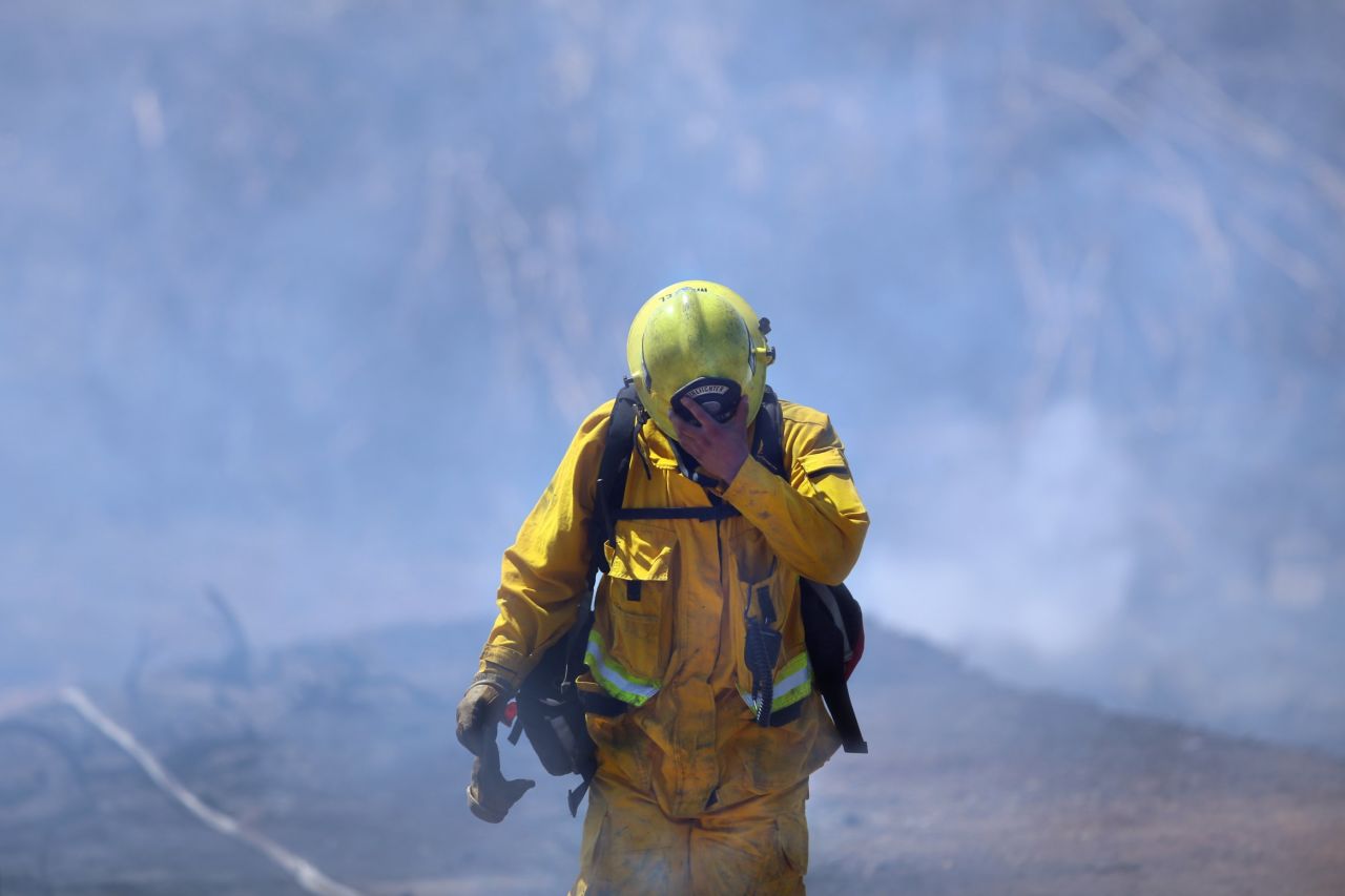 Firefighter Mike Martel walks through smoke while working to clean up after a weekend fire that ravaged the Montebello Hills area near Los Angeles on Monday, August 17.