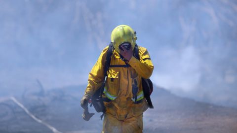 Firefighter Mike Martel walks through smoke while working to clean up after a weekend fire that ravaged the Montebello Hills area near Los Angeles on Monday, August 17.