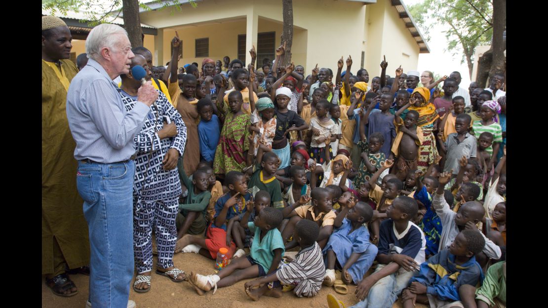 February 8, 2007. Savelugu Hospital, Northern Province, Ghana. President Jimmy Carter and his wife Rosalynn address Savelugu children on the seriousness of eradicating guinea worm disease. In this photo he has said "Hands up all those who have had Guinea Worm" and many of the children put up their hands.