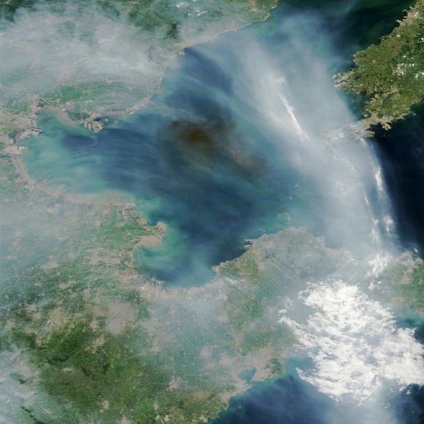 A dark plume of smoke drifts over the Bohai Sea off the east coast of China. The source of the smoke appears to be industrial fires caused by explosions at a port in Tianjin, China. The streams of light gray smoke in the image likely were caused by wildfires in eastern China. NASA's Terra satellite captured the images at 2:30 Universal Time (10:30 a.m. local time) on August 13, 2015.