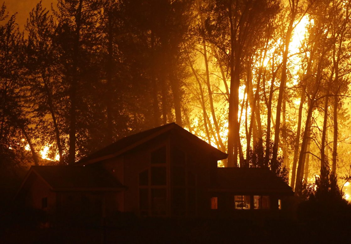 A wildfire burns behind a home in Twisp on August 20.