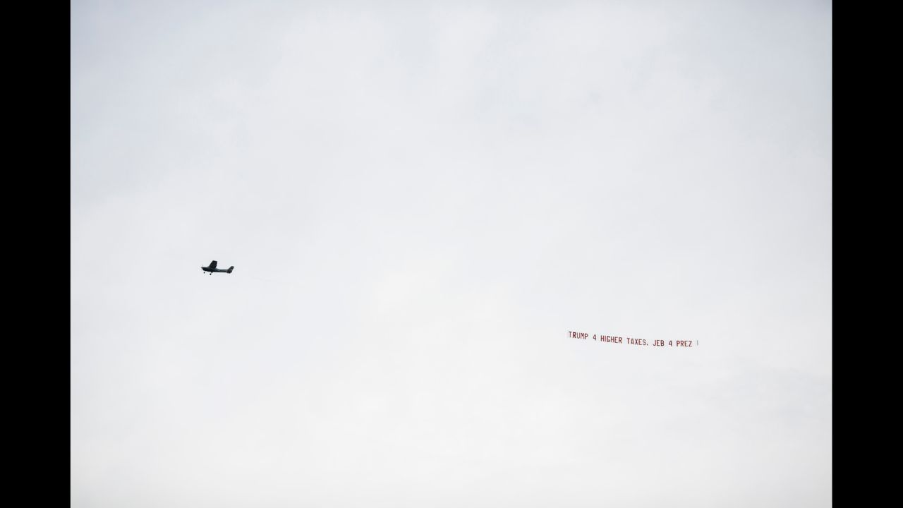 A pro-Jeb Bush plane flies by the stadium with banner "Trump 4 higher taxes. Jeb 4 Prez." Bush's official campaign said it emailed supporters in Alabama pointing out Trump's previous liberal positions on abortion, gun rights and tax issues.