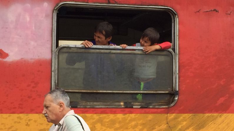 Father and son look out the window of a train in Macedonia.