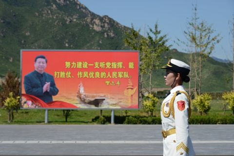 A female soldier stands in front of a billboard featuring Chinese president Xi Jinping on August 22.