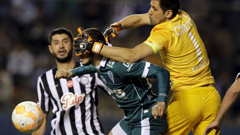 Libertad goalkeeper Rodrigo Munoz covers the face of Carlos Gonzalez, a forward for the Santiago Wanderers, as they vie for the ball during a Copa Sudamericana match Tuesday, August 18, in Asuncion, Paraguay. Libertad won the match 2-1 and advanced to the next stage of the tournament.