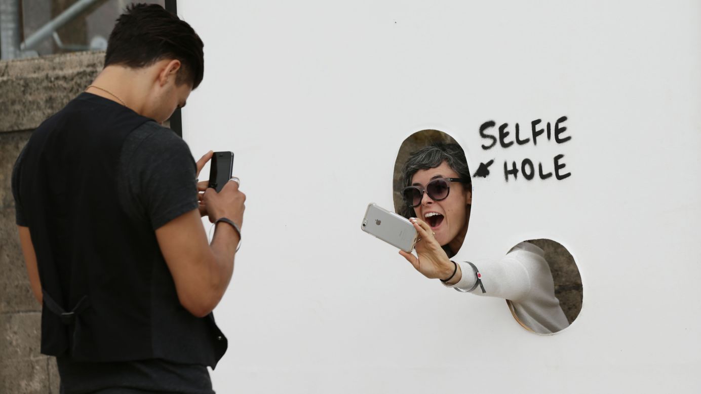 A visitor photographs herself through a "selfie hole" at <a href="http://www.cnn.com/2015/08/20/arts/gallery/banksy-dismaland/index.html" target="_blank">Banksy's biggest show to date, entitled "Dismaland"</a> in Somerset, England, on Thursday, August 20.