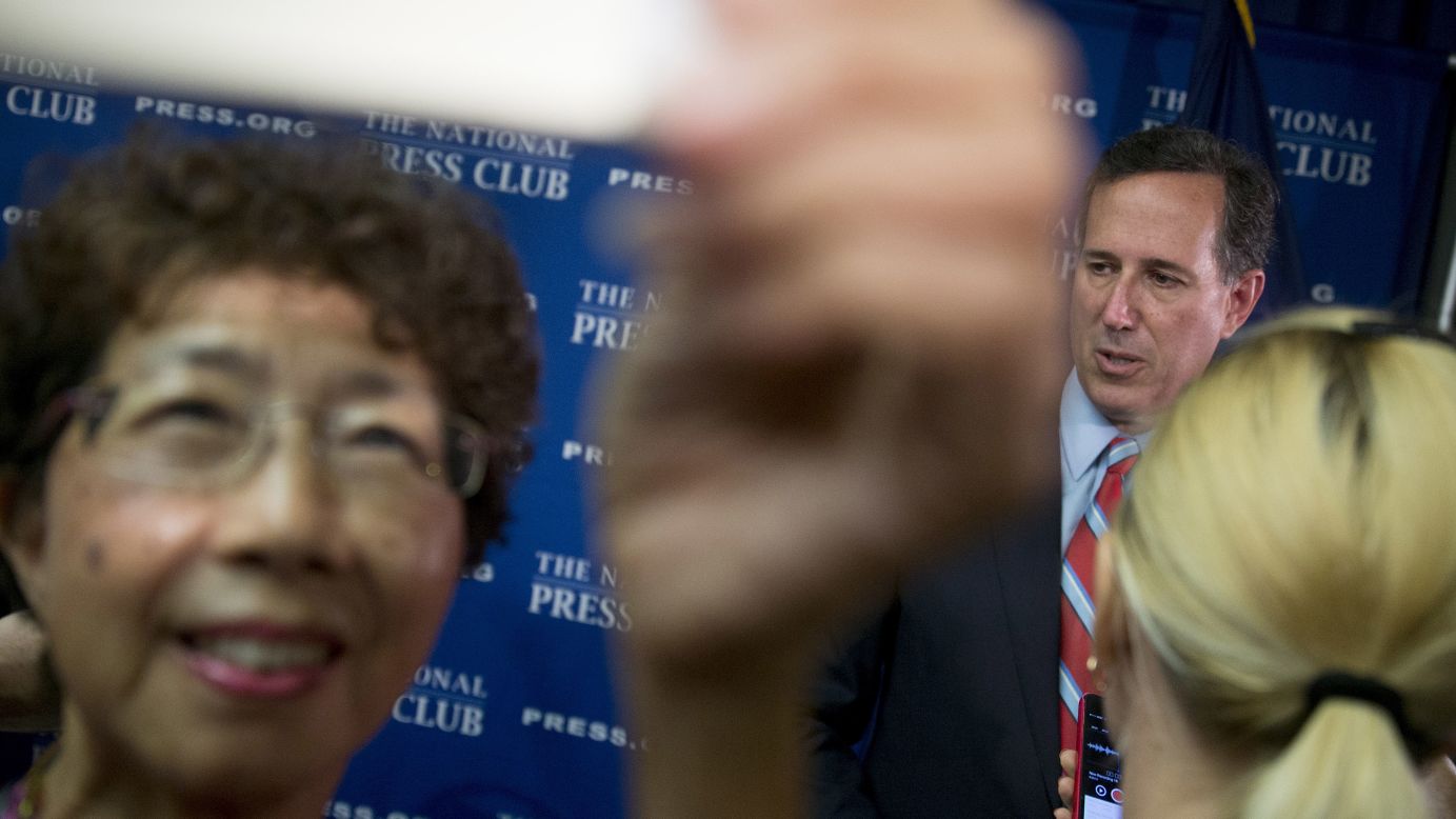 A woman takes a selfie with Republican presidential contender Rick Santorum after a news conference on the immigration system at the National Press Club in Washington on Thursday, August 20.