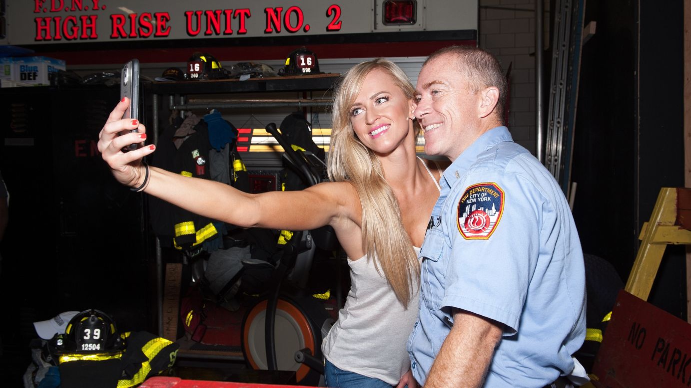 Professional wrestler Summer Rae poses for a selfie with a firefighter during WWE Answer the Call Tour on Thursday, August 20, in New York City.