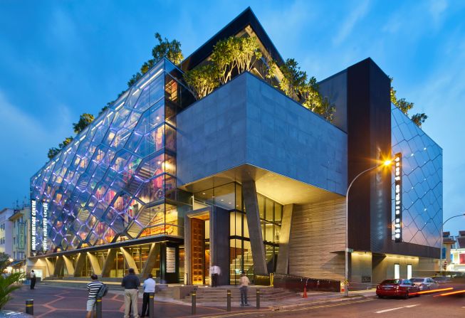 The Indian Heritage Centre glows like an urban lantern at night. Vibrant images feature on its colorful facade.<br />