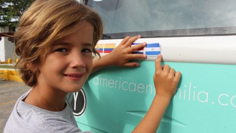 Dimas, 8, affixes the Nicaraguan flag on the back of the bus. The children have been taking turns with the flag stickers, but when they reach the United States, all four plan to put on the Stars and Stripes.
