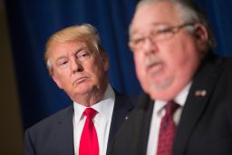 Republican presidential candidate Donald Trump listens as Sam Clovis speaks at a press conference at the Grand River Center on August 25, 2015 in Dubuque, Iowa. Clovis recently quit his position as Iowa campaign chairman for Rick Perry.