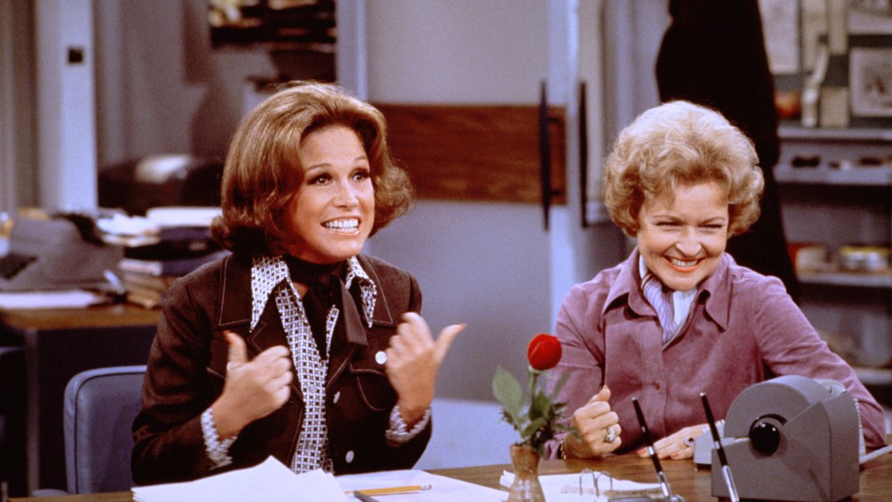 American actress Mary Tyler Moore (as Mary Richards) (left) gives a 'thumbs up' sign as she sits at her desk with Betty White (as Sue Ann Nivens) in a scene from 'The Mary Tyler Moore Show' in 1975.