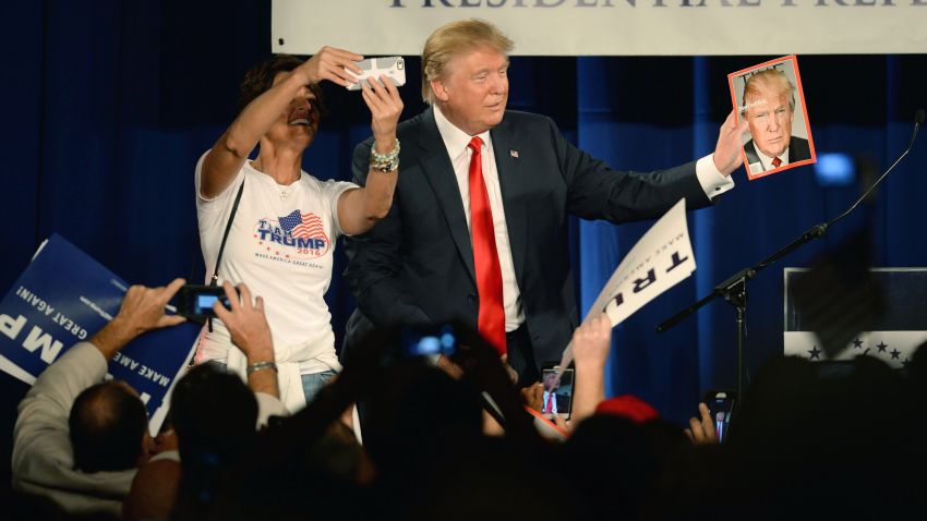 Republican presidential candidate Donald Trump holds a copy of TIME magazine with his likeness of the cover as a woman tries to take a selfie at the National Federation of Republican Assemblies (NFRA) Presidential Preference Convention at Rocketown on August 29, 2015 in Nashville, Tennessee.