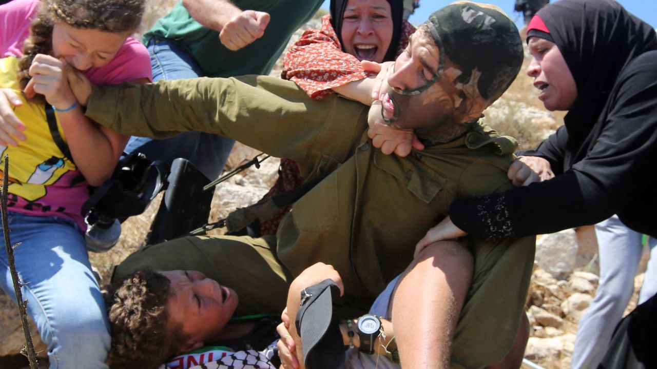 Women struggle to free the boy from the soldier.