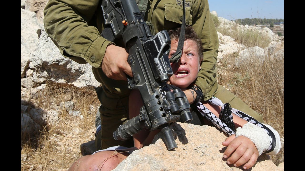 An armed Israeli soldier attempts to to arrest an 11-year-old Palestinian boy with his arm in a cast on Friday, August 28, during a protest against settlement construction in the village of Nabi Saleh in the West Bank.