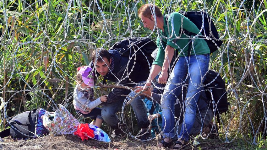 Migrants cross a border under the barbed fence near the village of Roszke on the Hungarian-Serbian border on August 28, 2015 . As Europe struggles with its worst migrant crisis since World War II, and Hungarian police has  so far this year intercepted some 141,500 migrants crossing into Hungary, mostly from neighboring Serbia.   AFP PHOTO / ATTILA KISBENEDEK        (Photo credit should read ATTILA KISBENEDEK/AFP/Getty Images)