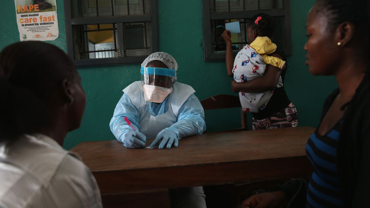 Health workers in protective clothing speak with new arrivals at a hospital in Monrovia, Liberia, on February 2, 2015.