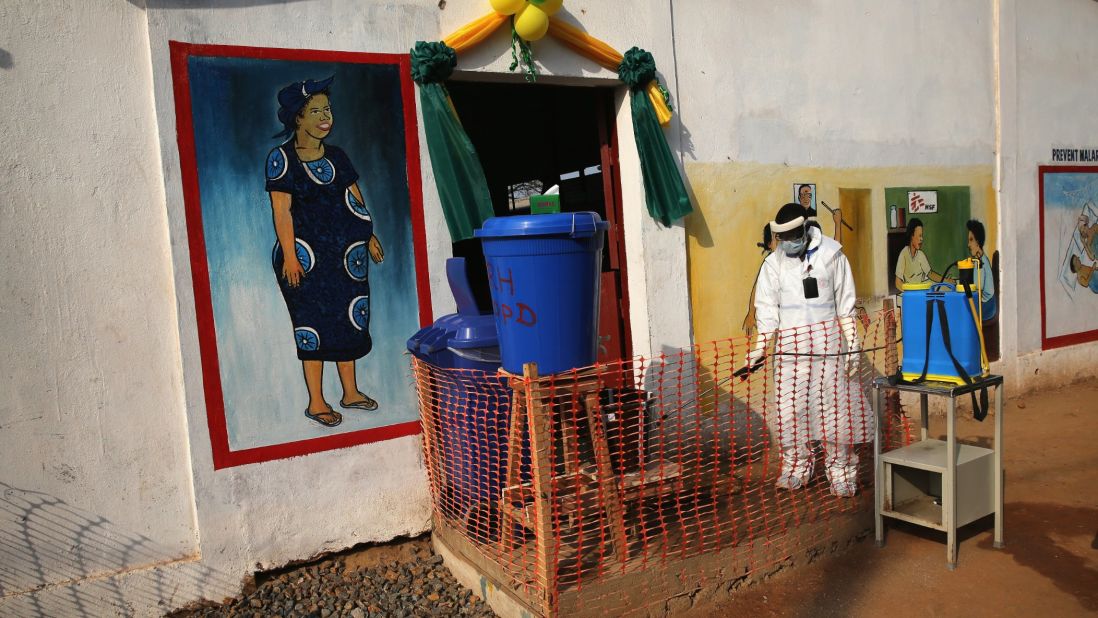 A health worker wearing protective clothing sprays the entrance of Redemption Hospital in Monrovia.  