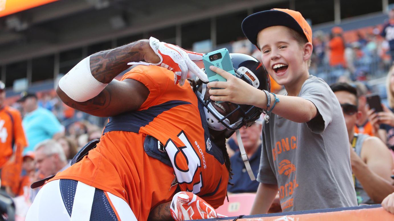 Denver Broncos safety Omar Bolden poses for a young fan's selfie before an NFL preseason game in Denver on Saturday, August 29.