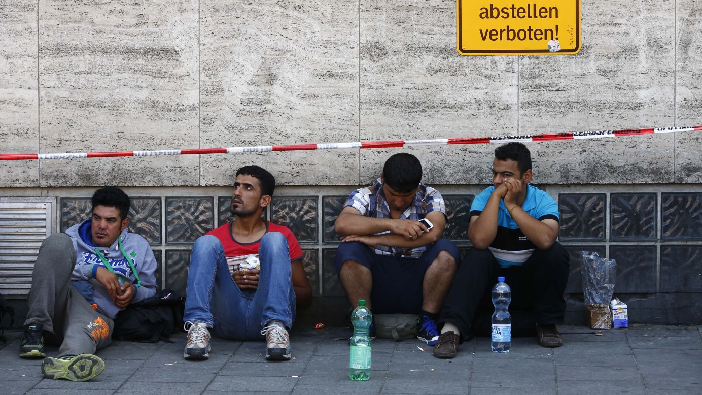 Migrants sit outside the main station in Munich as they wait for their chance to register.