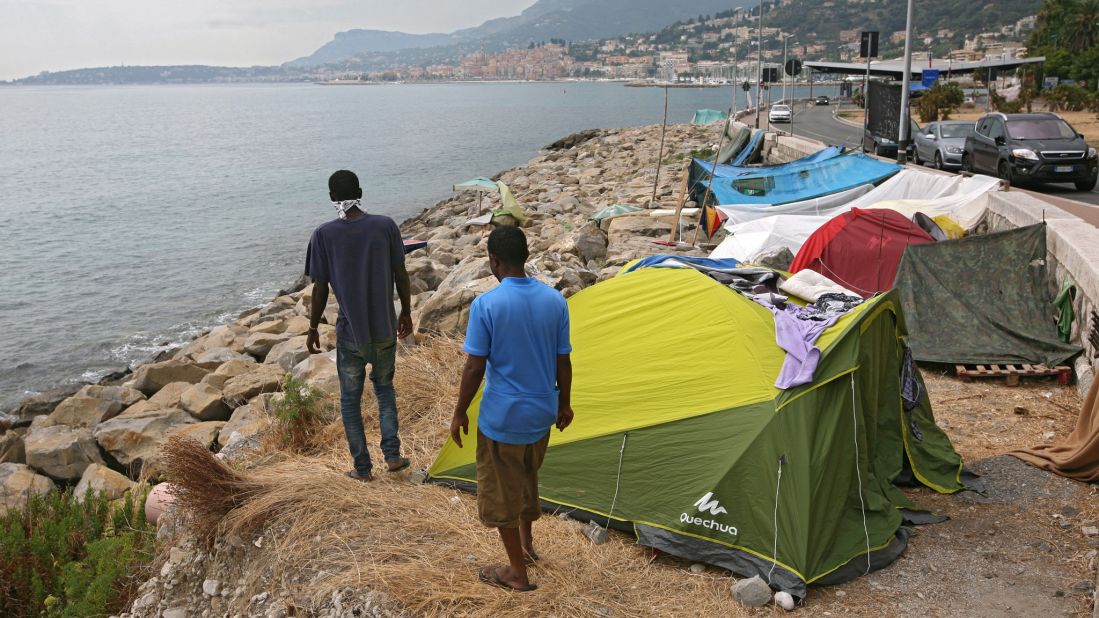 Migrants walk on a rocky beach in Ventimiglia, Italy, where they set up camp near the French border.