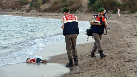 Authorities stand near Alan's lifeless body on September 2, 2015. This photo went viral around the world, often with a Turkish hashtag that means "Flotsam of Humanity."