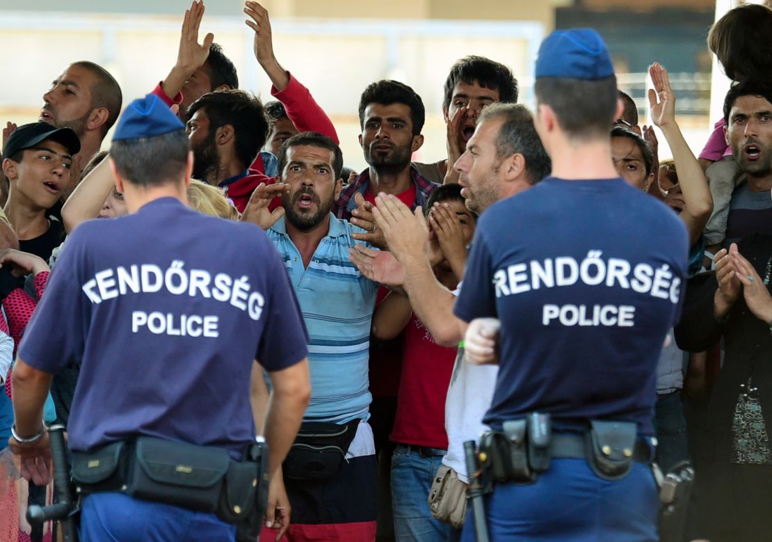 Hungarian police officers face a group of Syrian migrants on the platform of the Kobanya-Kispest station, Budapest suburb, on September 2, 2015, as the refugees refused to board a train to the Debrecen camp. 