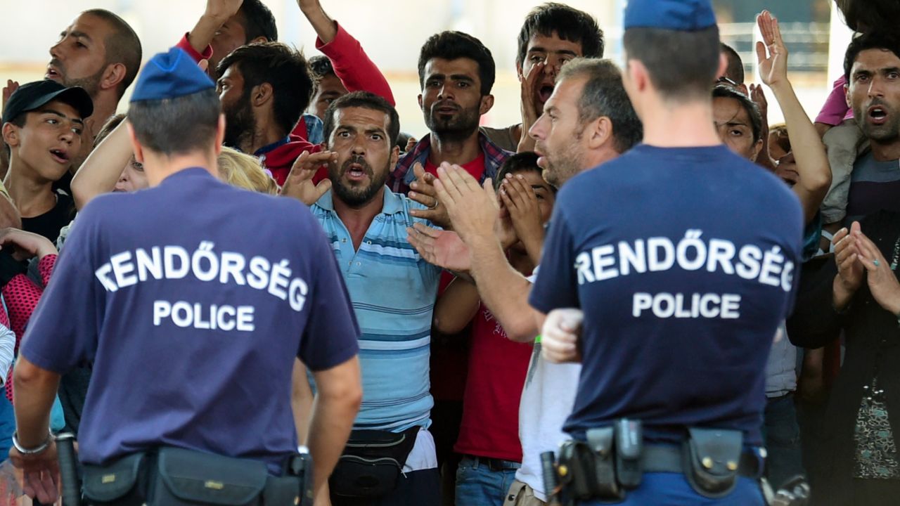 Hungarian police officers face a group of Syrian migrants on the platform of the Kobanya-Kispest station, Budapest suburb, on September 2, 2015, as the refugees refused to board a train to the Debrecen camp.
