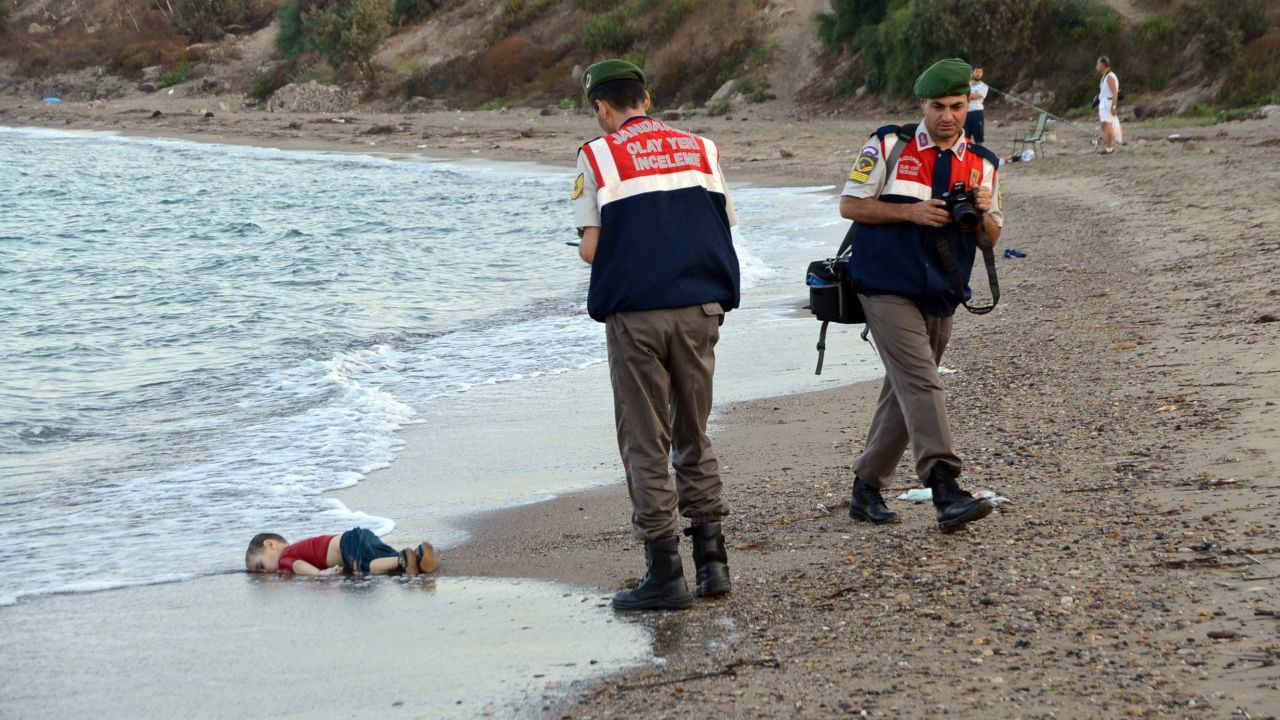 Authorities stand near the body of 2-year-old Alan Kurdi on the shore of Bodrum, Turkey, in September 2015. Alan, his brother and their mother <a href=