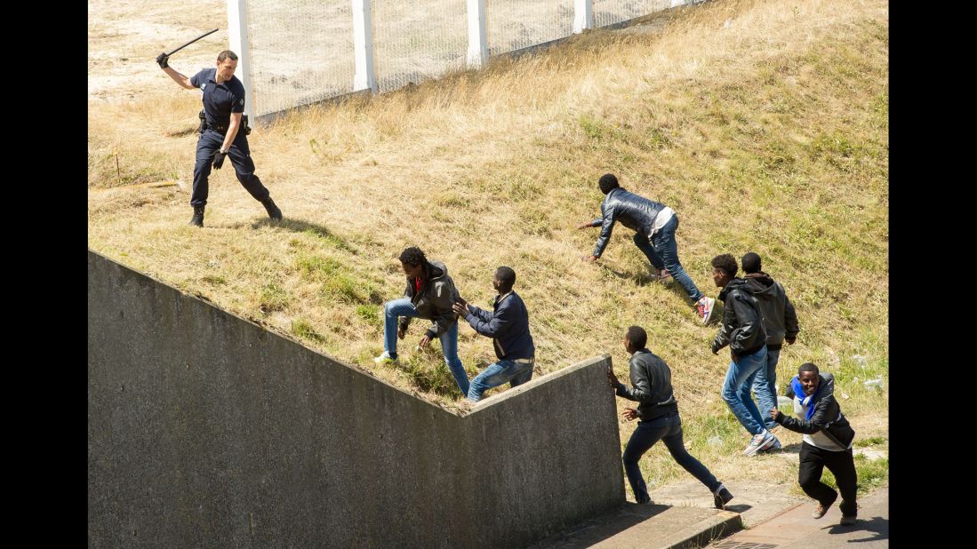 A police officer in Calais, France, tries to prevent migrants from heading for the Channel Tunnel to England in June 2015.
