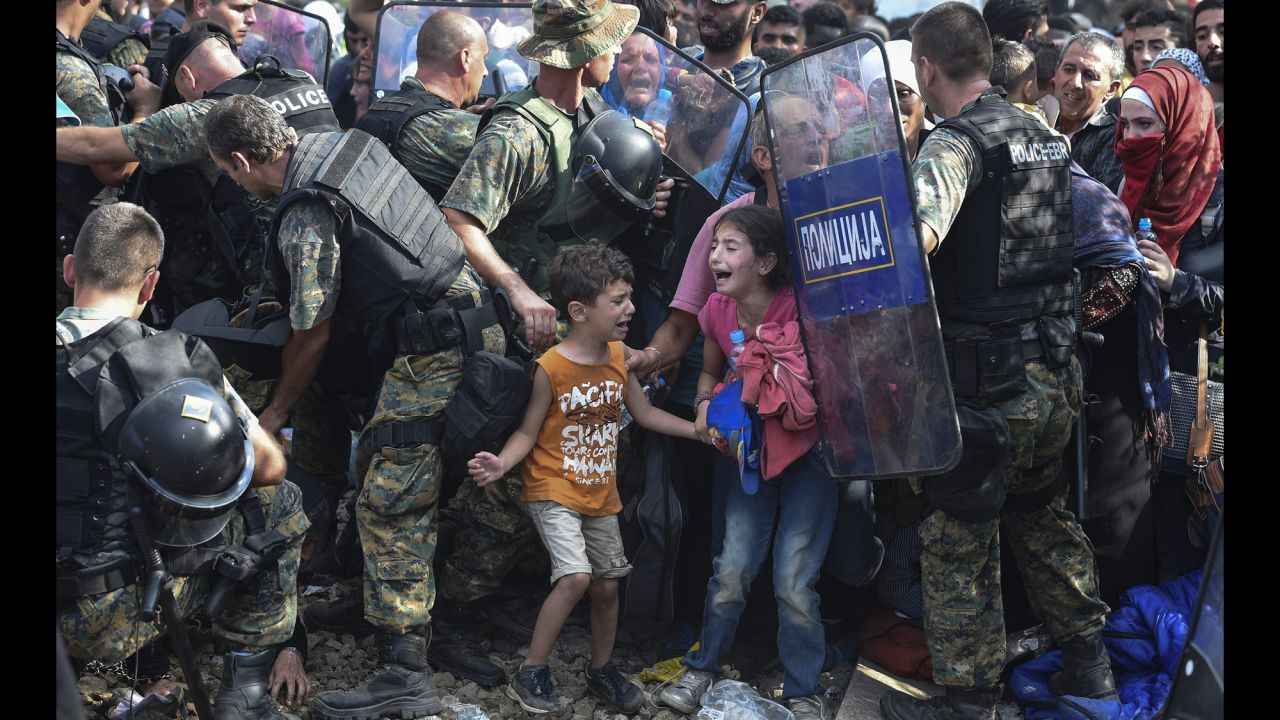 Children cry as migrants in Greece try to break through a police cordon to cross into Macedonia in August 2015. Thousands of migrants -- most of them fleeing Syria's bitter conflict -- were stranded in a <a href=