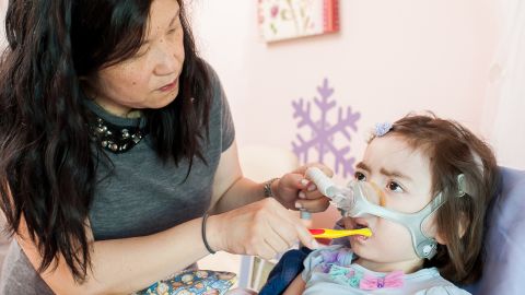 Julianna, who has Charcot-Marie-Tooth disease, once had nearly full use of her arms, but now can't even hold a small toy without help. Her mother, Michelle Moon, brushes her teeth. 