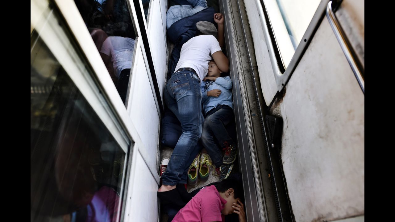 Syrian refugees sleep on the floor of a train car taking them from Macedonia to the Serbian border in August 2015. <a href=