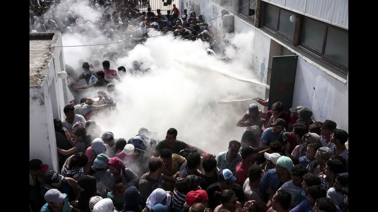 Policemen try to disperse hundreds of migrants by spraying them with fire extinguishers during a registration procedure in Kos, Greece, in August 2015.