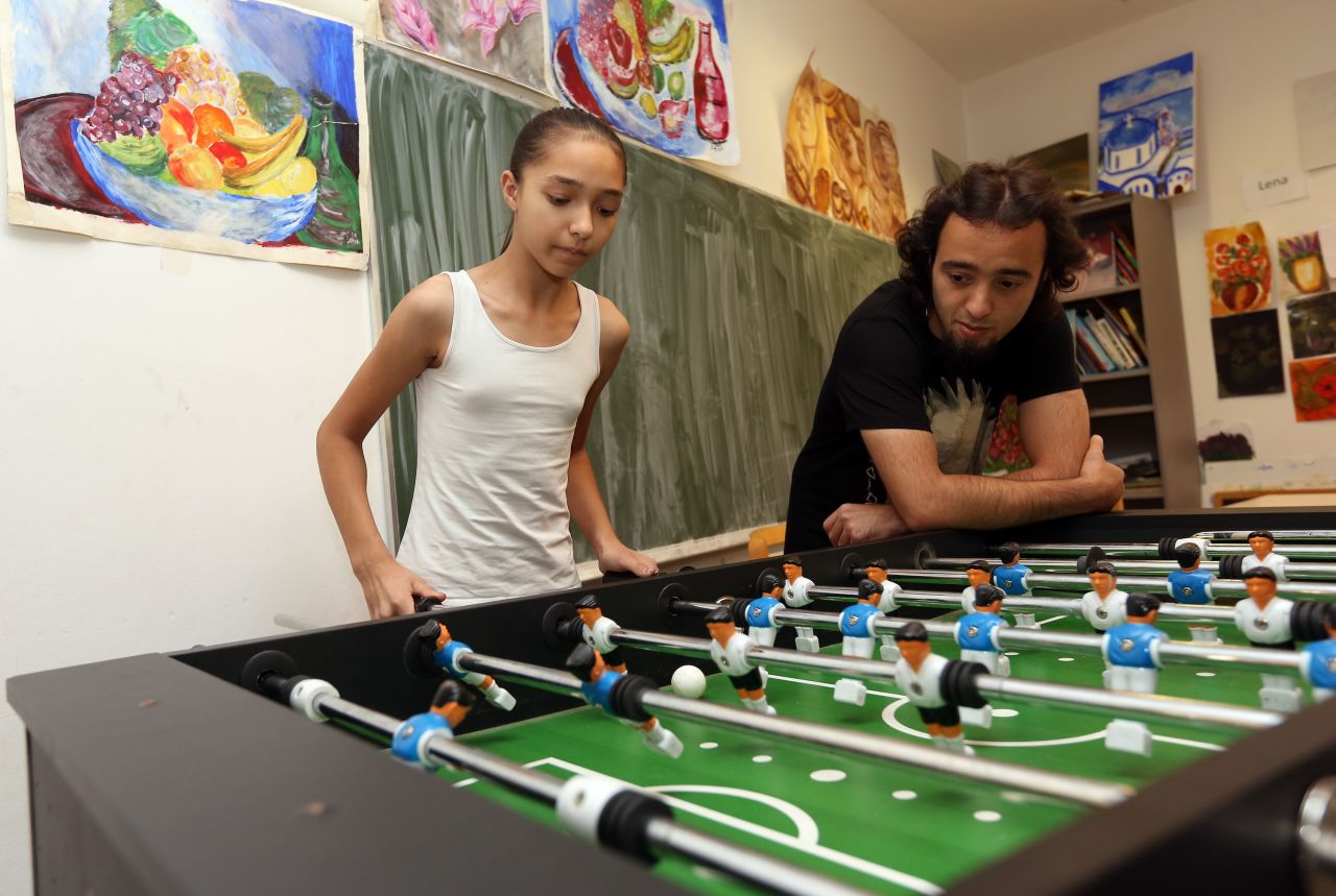 Eleven-year-old Serbian refugee Kristina (L) is pictured playing table football, or foosball, with Iranian refugee Andabili Hossein at a temporary home providing assistance for refugees on August 5, 2015 in Berlin, Germany.