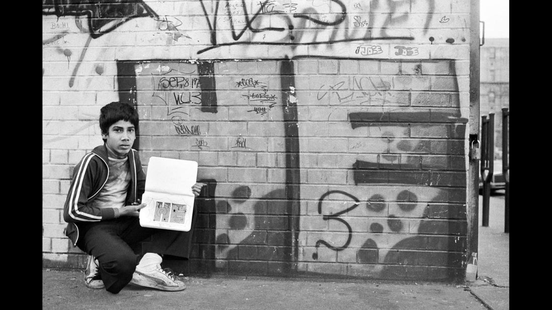 The boy in this photograph is showing a notebook where he practices his tag (or signature) to write on walls. Cooper says this image first inspired her to shoot photographs of graffiti artists and their work. A conversation with the boy pictured above -- known as HE3 -- first exposed her to the use of tags in graffiti. Tags are seen as an artistic interpretation of one's nickname, often used as a form of self expression and identity. HE3 also introduced Martha to famed street artist Dondi.