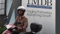 A motorist rides past a hoarding at the construction site of the 1 Malaysia Development Berhad (1MDB) flagship Tun Razak Exchange in Kuala Lumpur on July 8, 2015. A government task force investigating a Malaysian state-owned investment fund seized documents from its offices on July 8 after a probe allegedly found hundreds of millions of dollars in the prime minister's personal bank accounts. AFP PHOTO / MANAN VATSYAYANA     