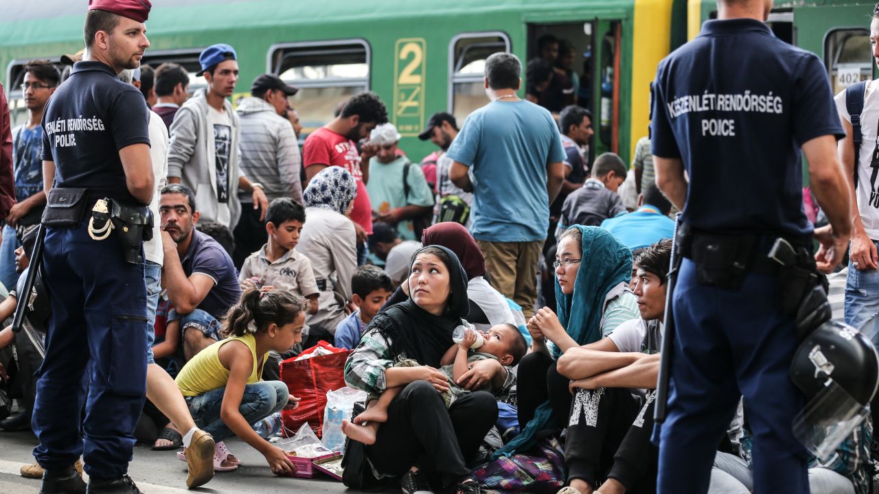Police stand guard as migrants sit on the platform of Keleti station after it was reopened this morning in central Budapest on September 3, 2015 in Budapest, Hungary. Although the station has reopened all international trains to Western Europe have bee cancelled. According to the Hungarian authorities a record number of migrants from many parts of the Middle East, Africa and Asia are crossing the border from Serbia. Since the beginning of 2015 the number of migrants using the so-called Balkans route has exploded with migrants arriving in Greece from Turkey and then travelling on through Macedonia and Serbia before entering the EU via Hungary. The massive increase, said to be the largest migration of people since World War II, led Hungarian Prime Minister Victor Orban to order Hungary's army to build a steel and barbed wire security barrier along its entire border with Serbia, after more than 100,000 asylum seekers from a variety of countries and war zones entered the country so far this year.