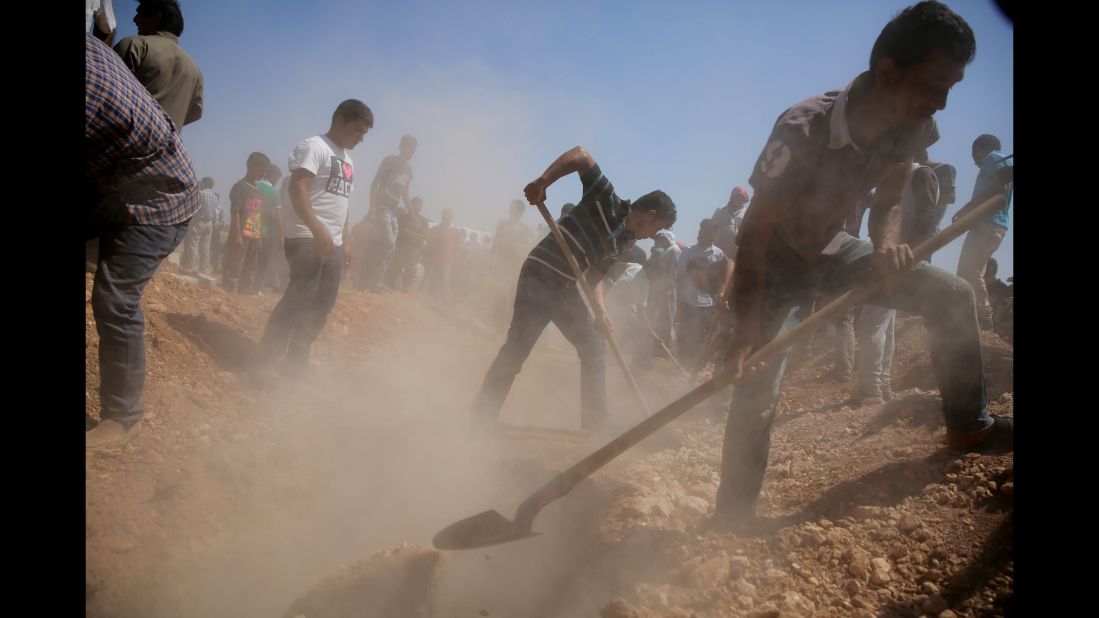 Men dig graves for the three coffins in Kobani on September 4, 2015.