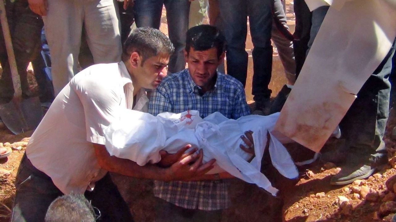 Kurdi holds Alan's body before burying him in Kobani on September 4, 2015.