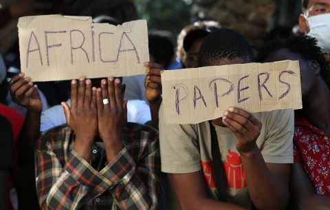 African men hold up signs urging Greek authorities to issue their official immigration papers in Kos on August 28.