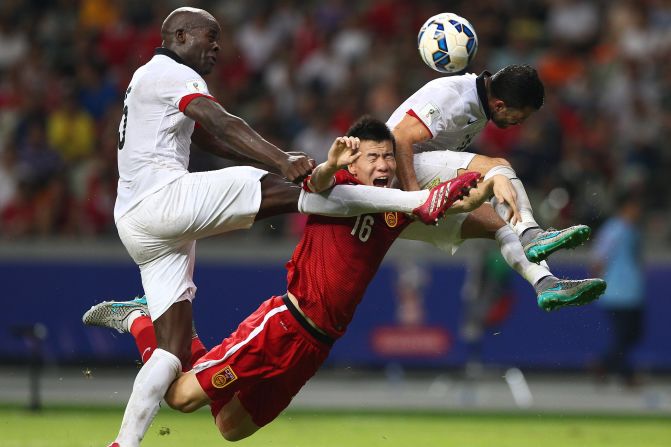 Sun Ke (C) of China tussles for the ball against Jean Jacques Kilama (L) of Hong Kong.