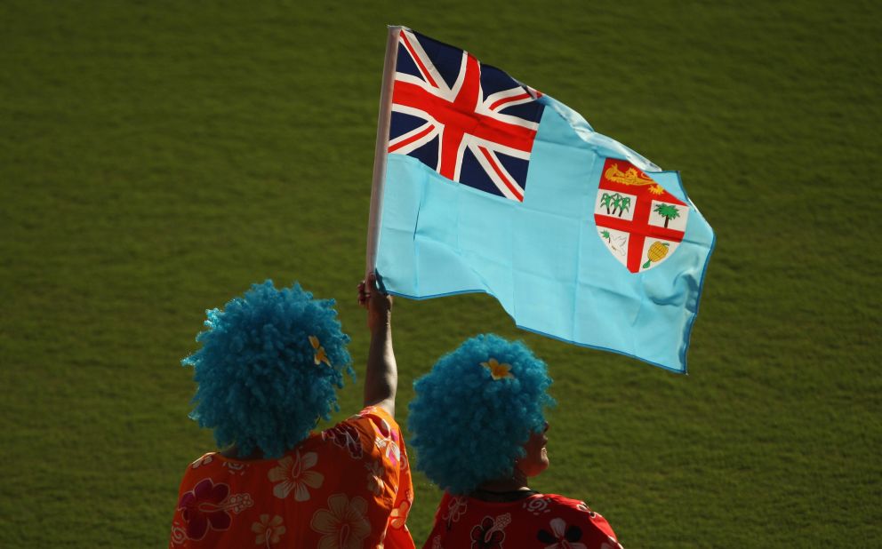 Which island includes a bunch of bananas on its national flag? "The<a href="http://www.crwflags.com/fotw/flags/fj.html" target="_blank" target="_blank"> flag (of Fiji) </a>is blue with the Fijian arms drawn in gold and a carved whale tooth on a rope. Coat-of-Arms. According to Smith 1985, the specimens depicted in the Fijian coat-of-arms are three sugar canes, a coconut palm, a dove with olive branch and a bunch of bananas. The lion in the chief is holding a peeled coconut."<br />
