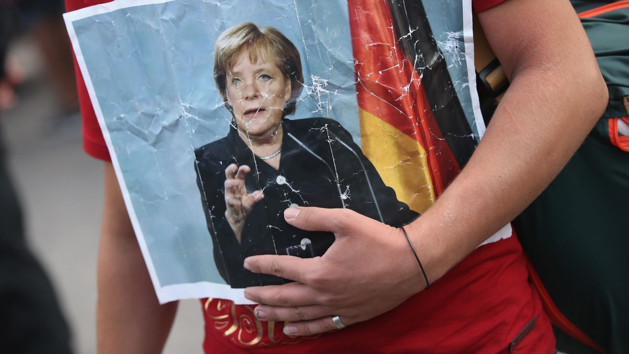 A Syrian refugee holds a picture of German Chancellor Angela Merkel as he and hundreds of others arrive in Munich.