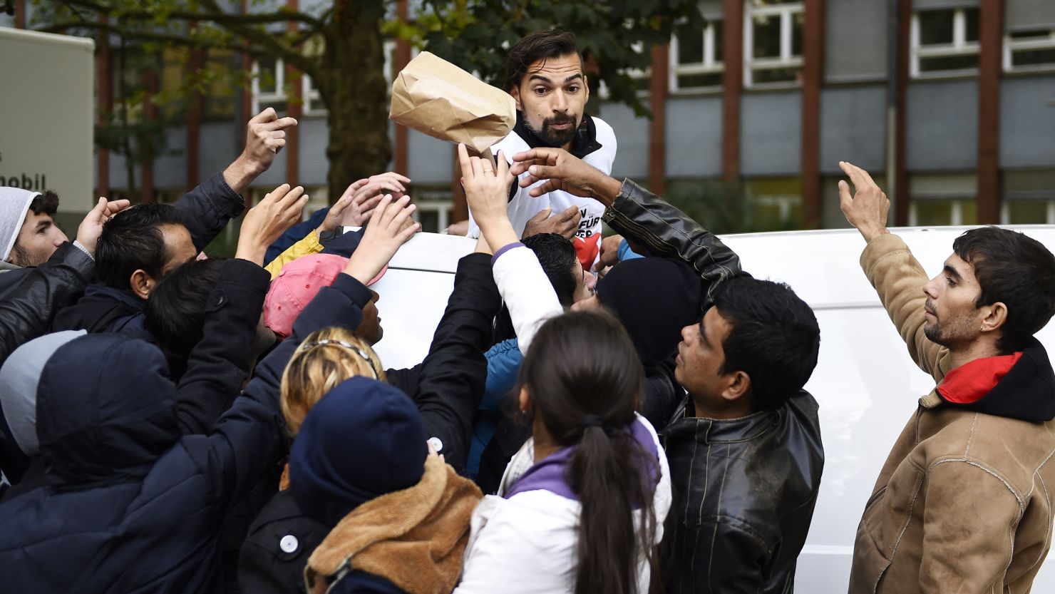 A volunteer hands over care bags to refugees at the yard of the Central Registration Office for Asylum Seekers (Zentrale Aufnahmestelle fuer Asylbewerber, or ZAA) of the State Office for Health and Social Services (Landesamt fuer Gesundheit und Soziales, or LAGeSo) in Berlin on September 7, 2015. The numbers of migrants have spiked since September 4, 2015, when Austria and Germany threw open their borders and eased travel restrictions to allow in thousands who had made it to Hungary, which has balked at the influx.