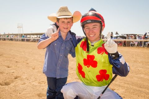 A jockey poses with a young fan before a race. 